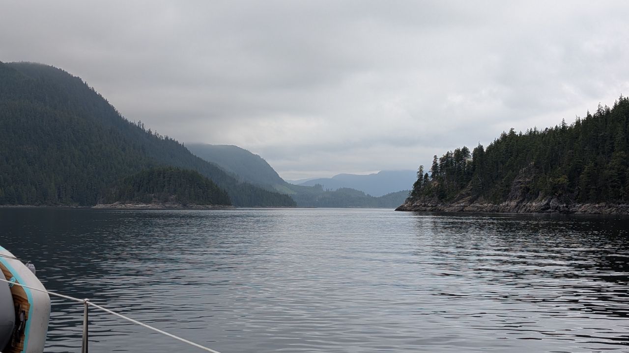 Misty forested mountains along a calm channel approaching Greene Point Rapids