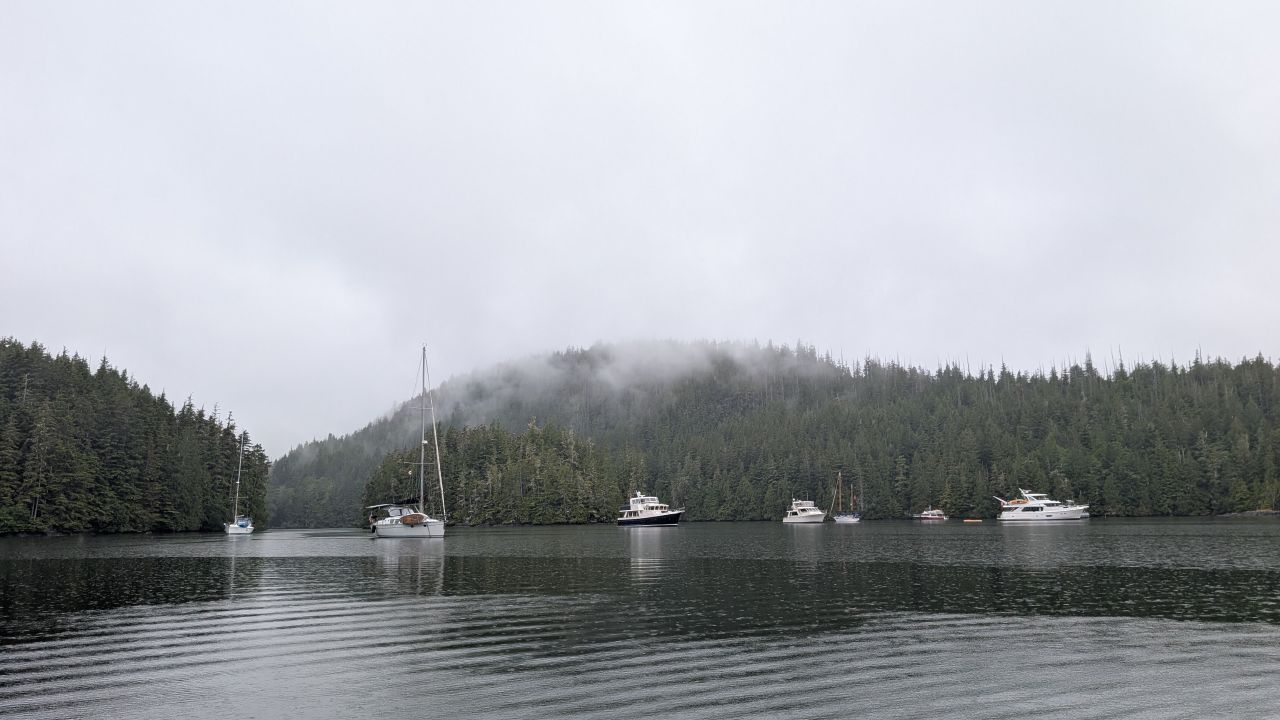 Boats anchored in foggy Waddington Bay surrounded by misty forested mountains