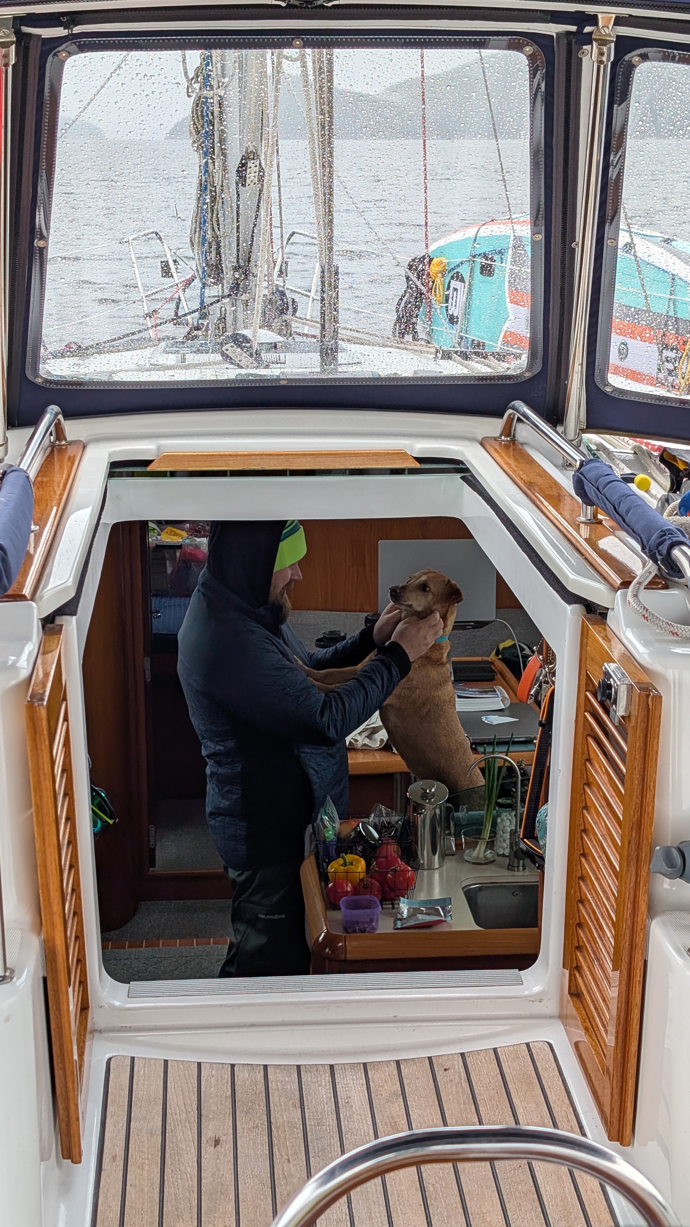 Brian petting Maui in the companionway of SV Yahara on a rainy day