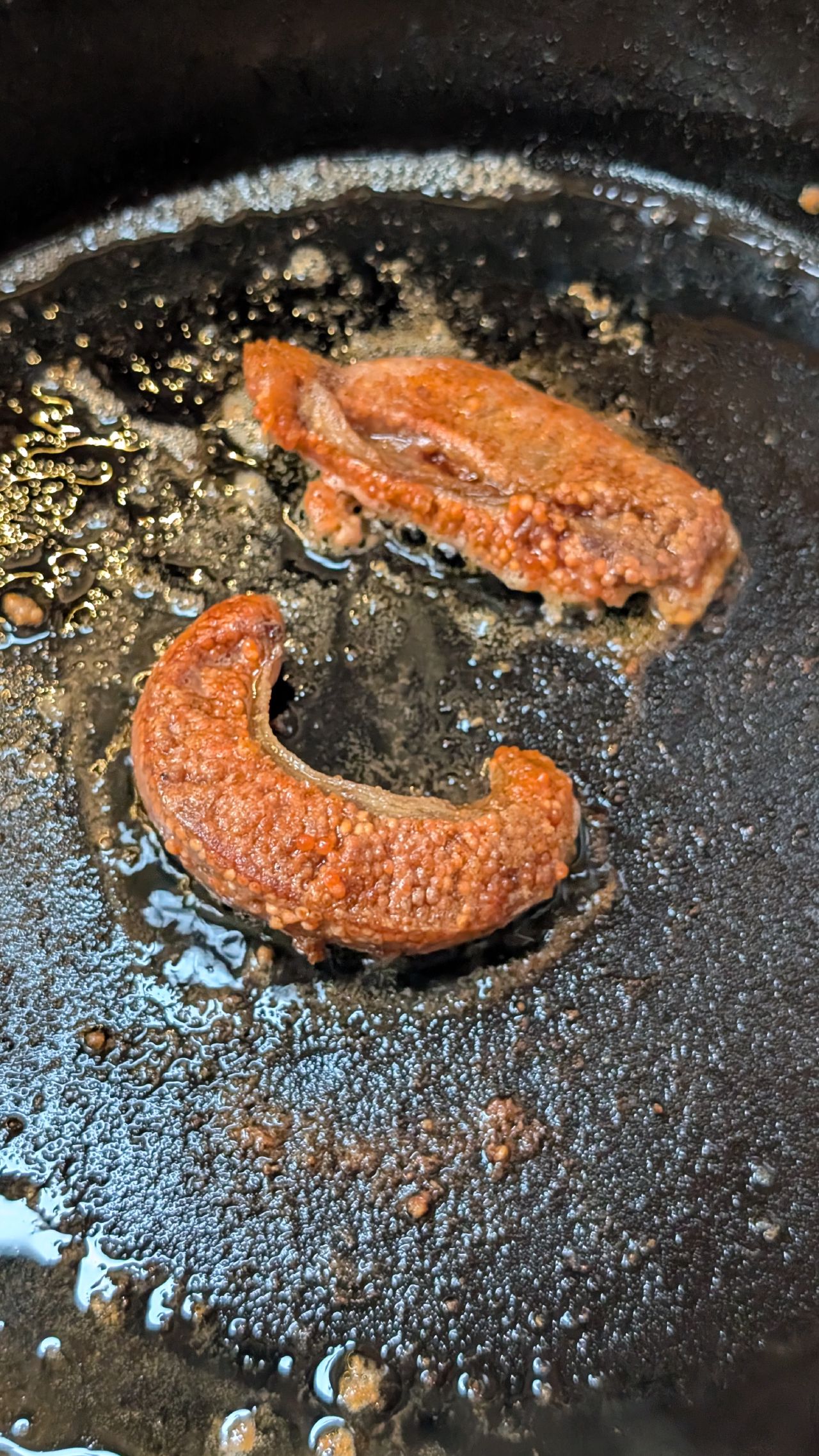 Pan-fried salmon roe sizzling in a cast iron skillet on the boat