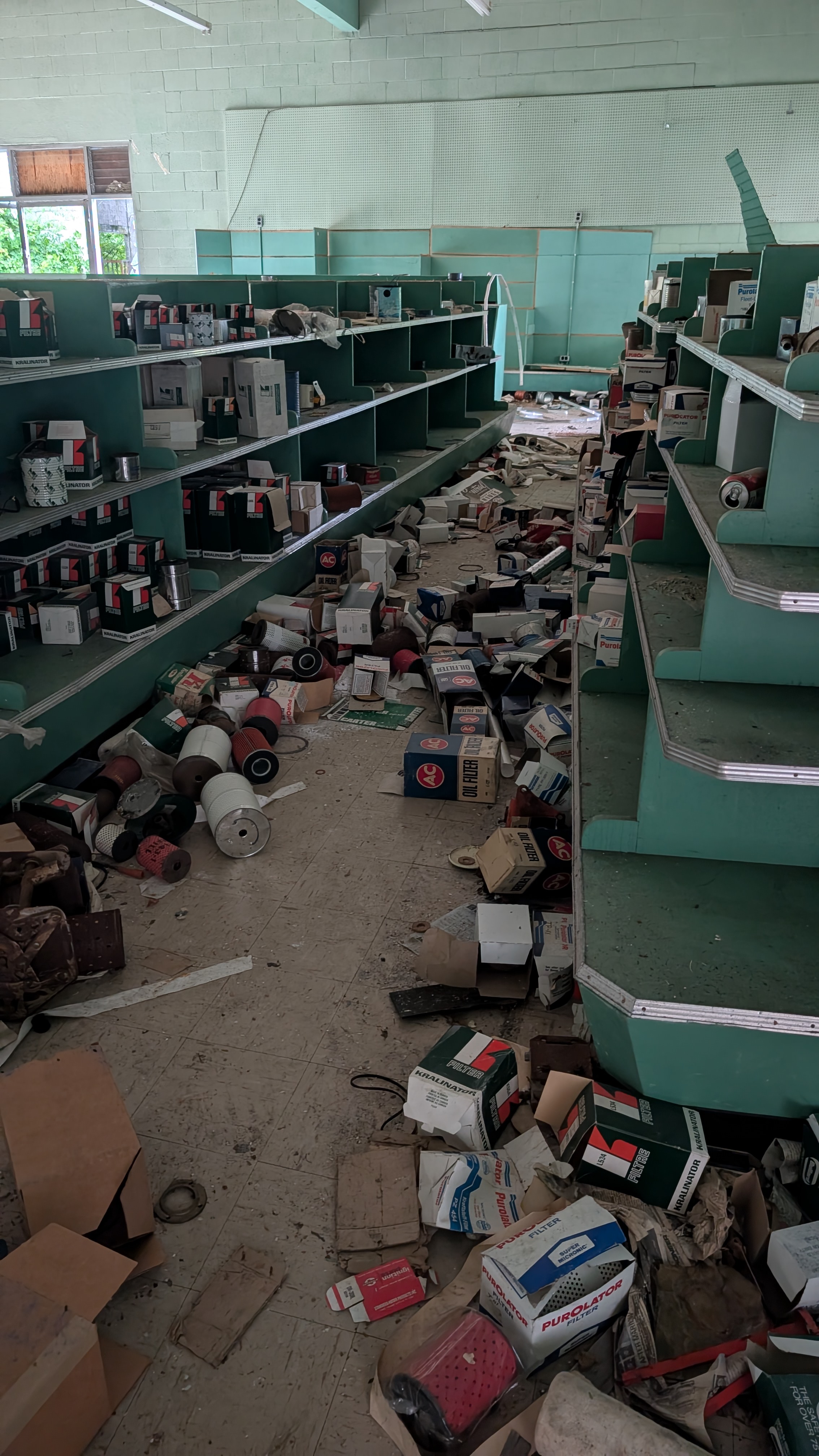Abandoned store with green shelves and scattered oil filters and supplies in Namu