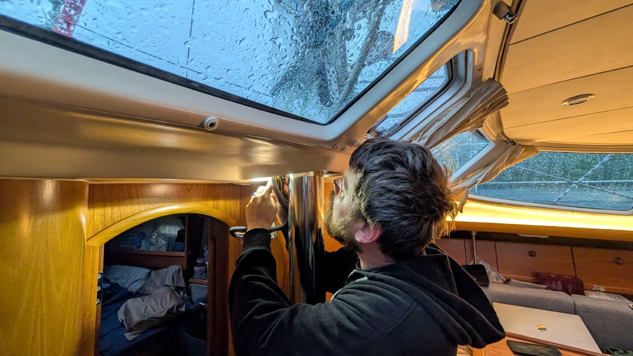 Brian inspecting a leak near the overhead hatch below deck during a rainstorm