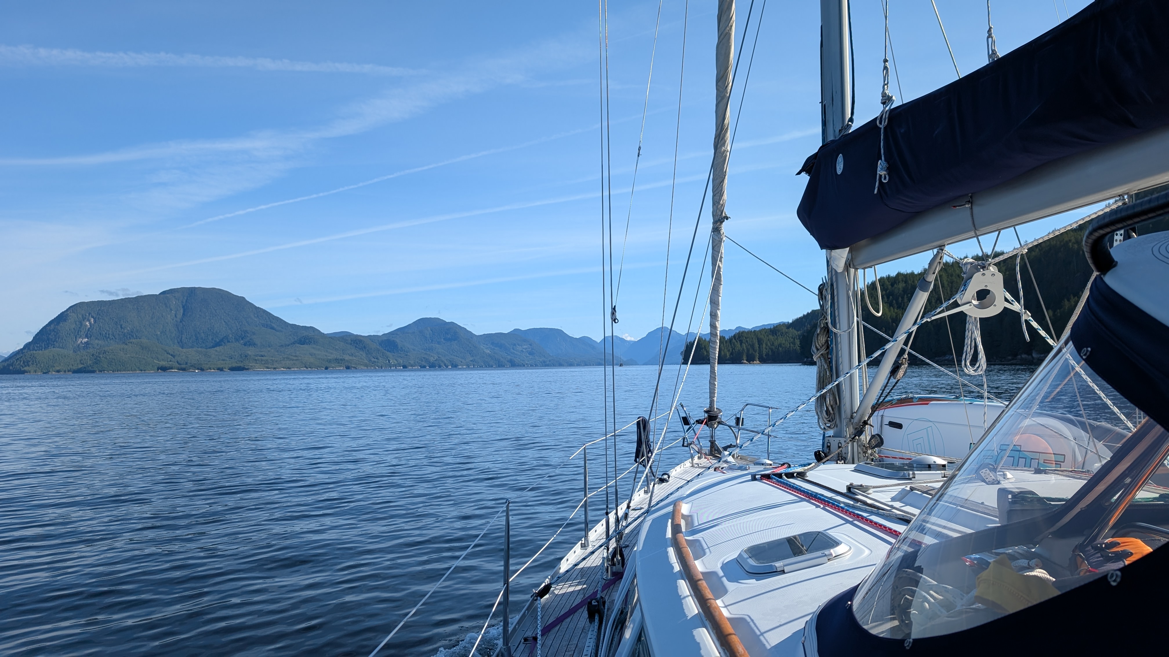View along the foredeck of SV Yahara with blue sky and mountains on the passage