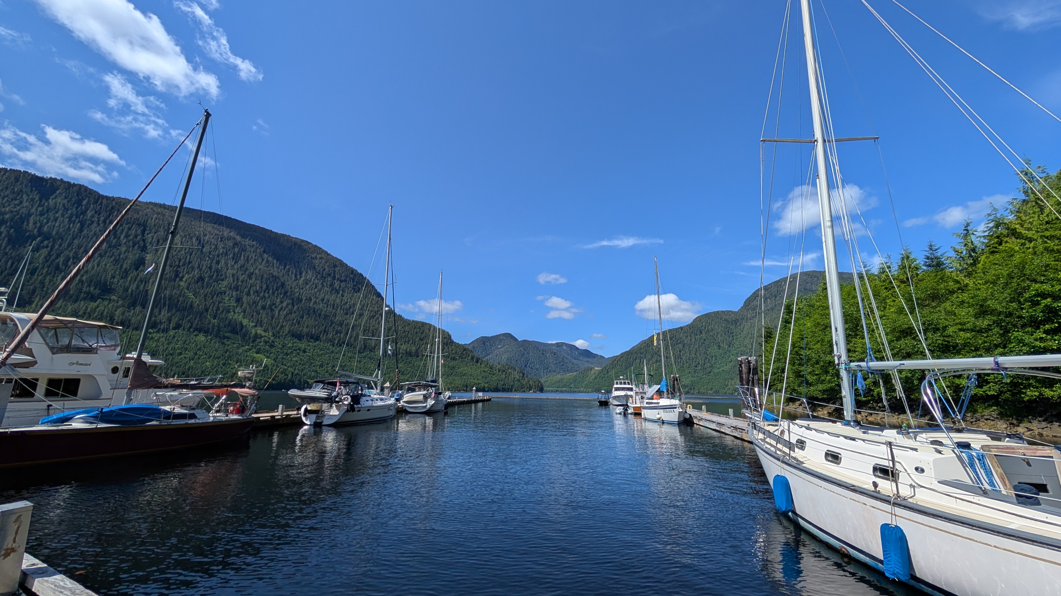 Boats docked at the Ocean Falls marina surrounded by steep mountains on a sunny day