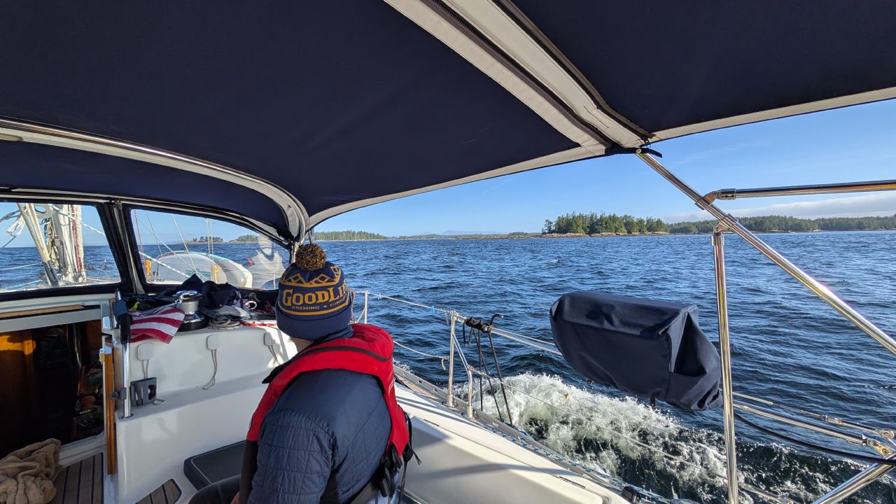 Brian at the helm in life jacket and beanie heading into choppy seas on the passage to Oliver Cove