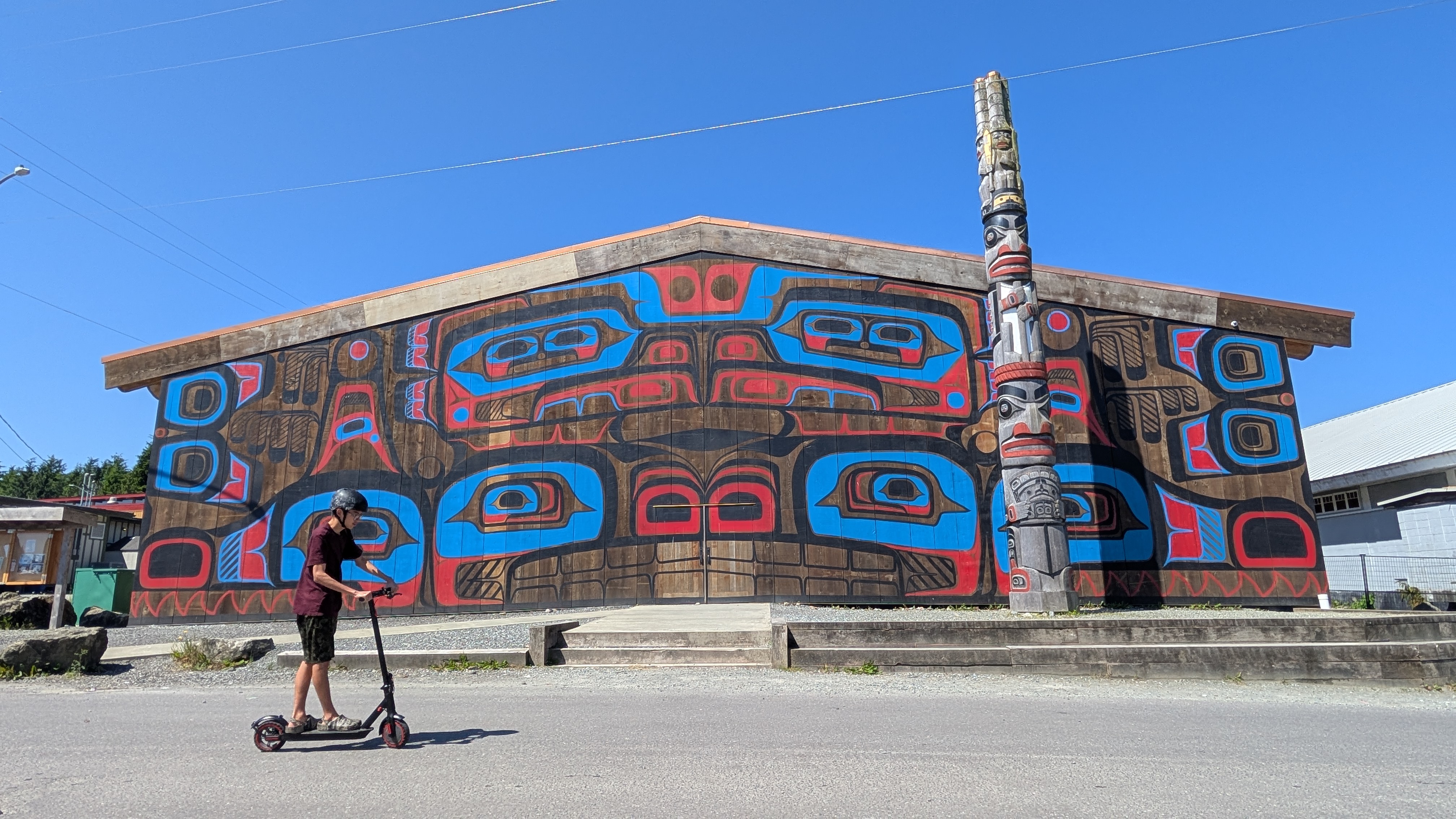 First Nations big house in Bella Bella with vibrant painted facade and totem pole out front
