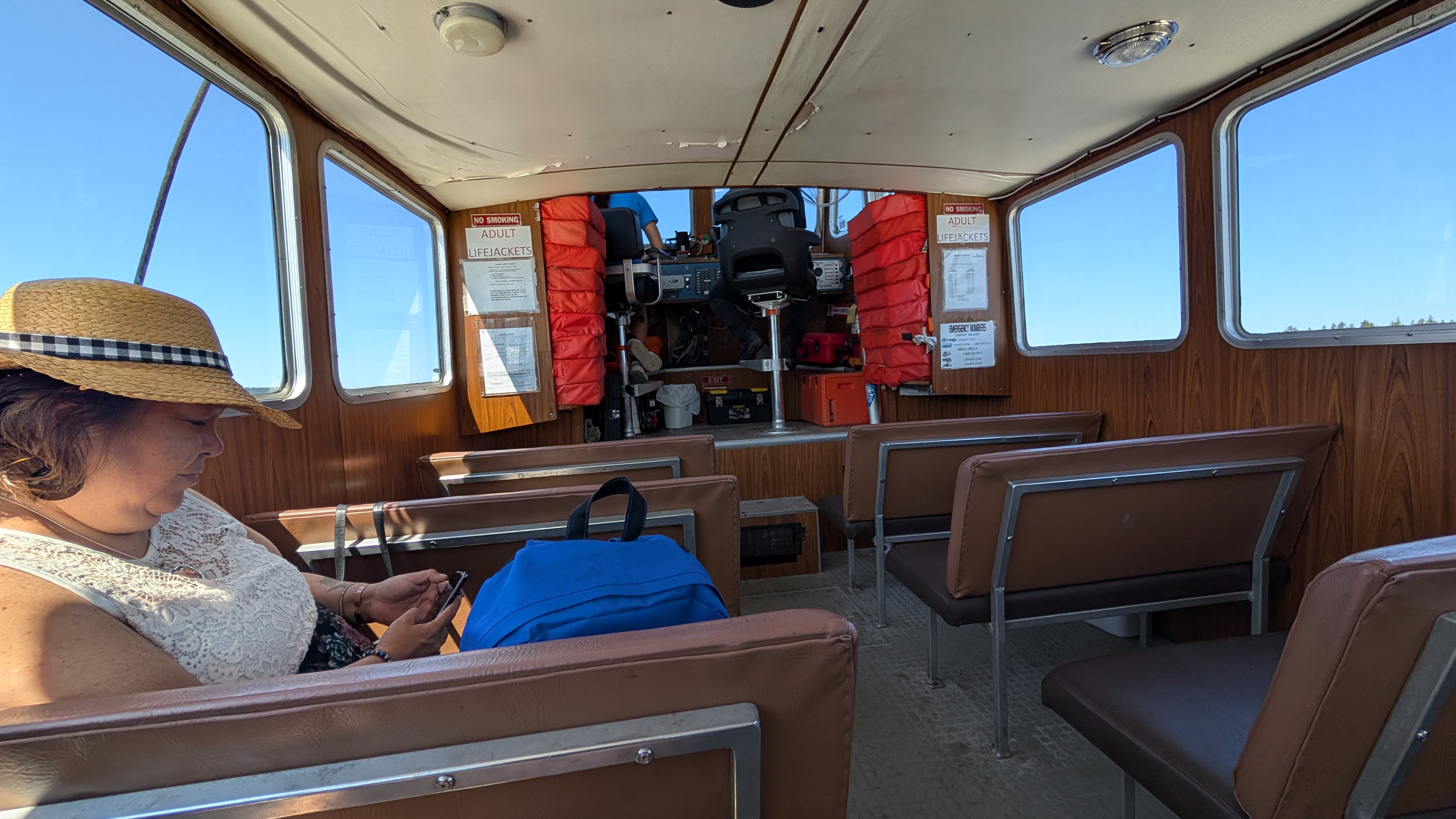 Rachel riding the water taxi from Shearwater to Bella Bella, checking her phone in the cabin