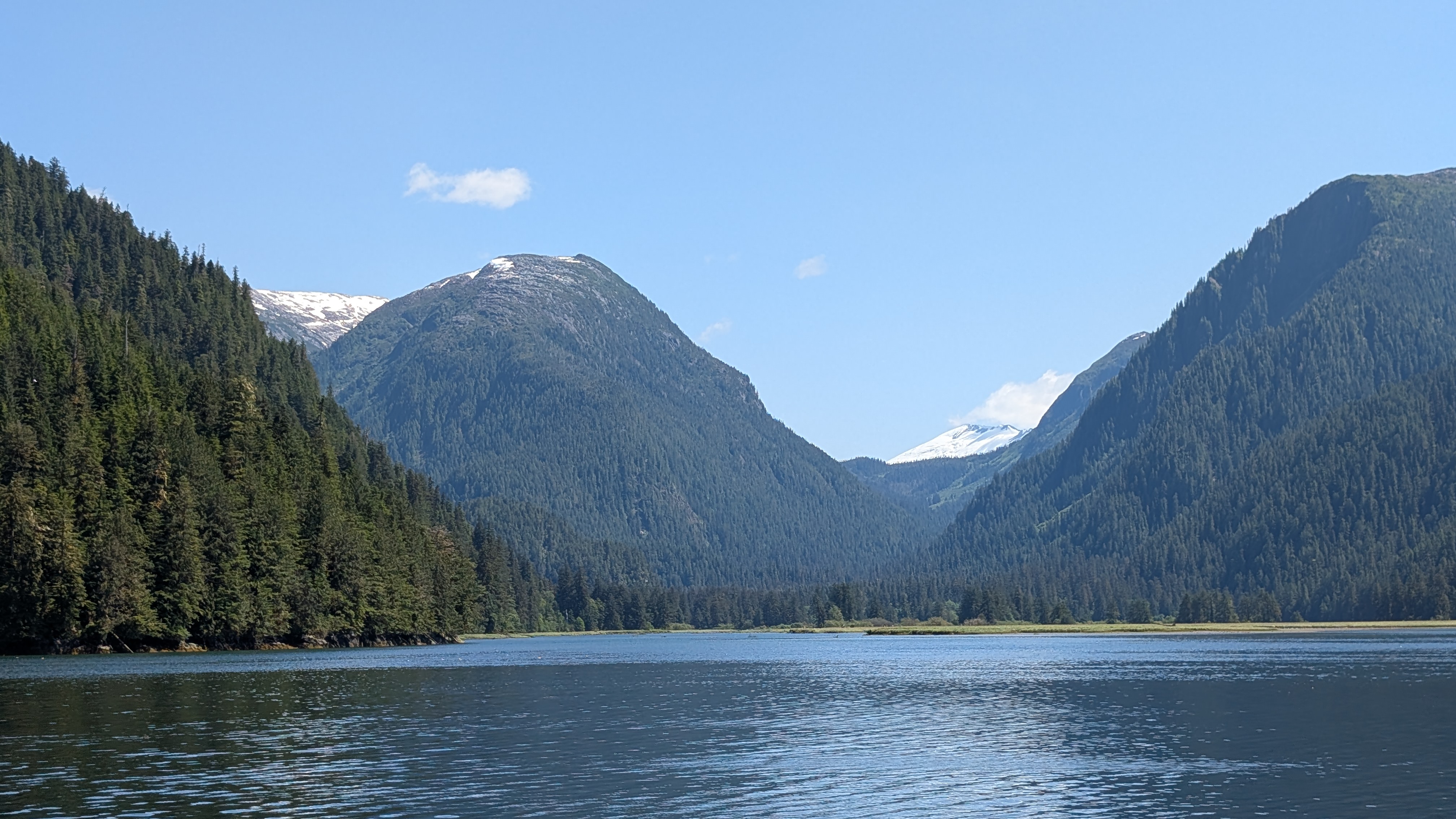 Snow-capped mountains towering over the calm waters of Khuntz Bay on a clear day