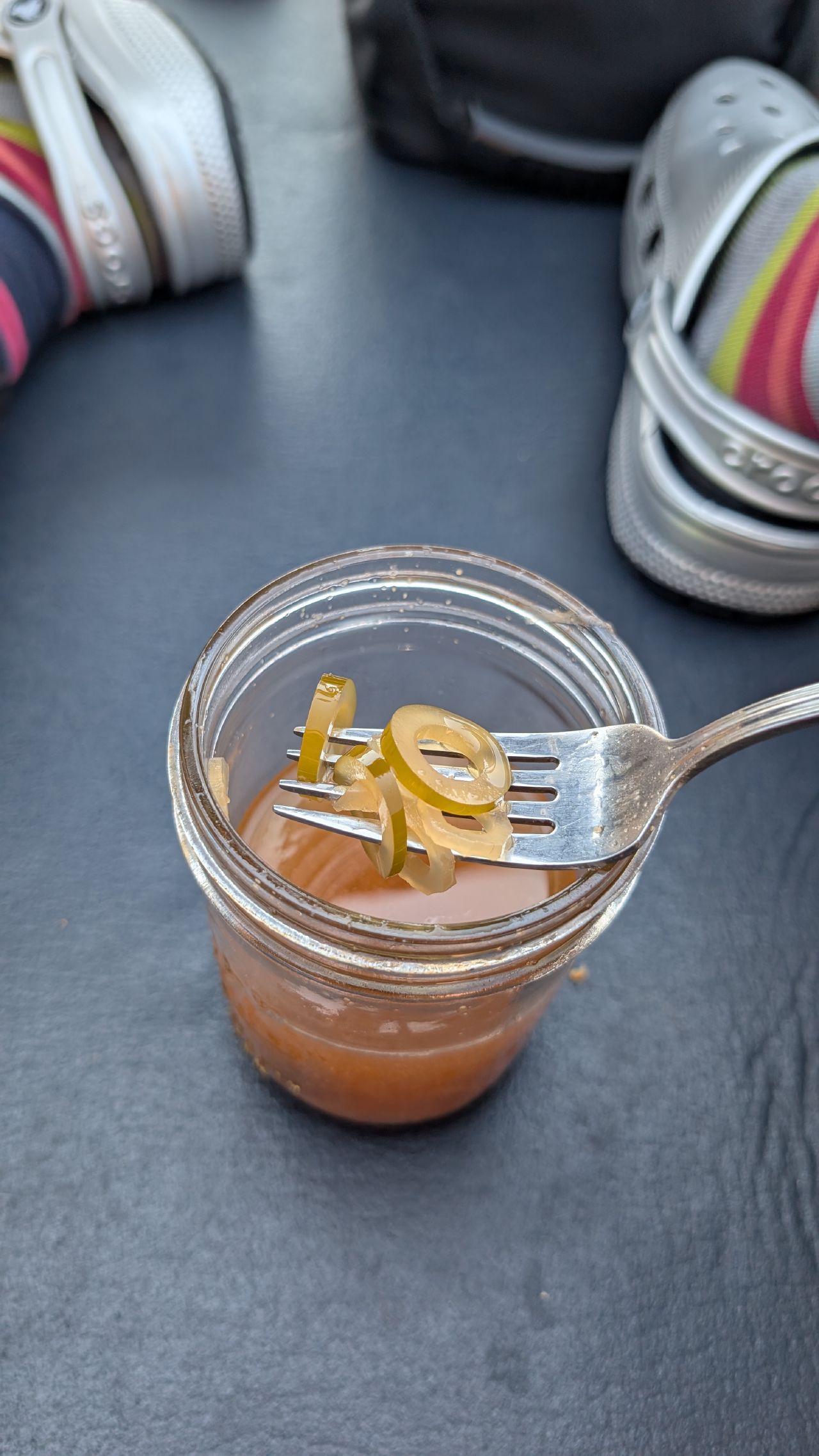 Homemade bull kelp pickles on a fork from a mason jar in the cockpit