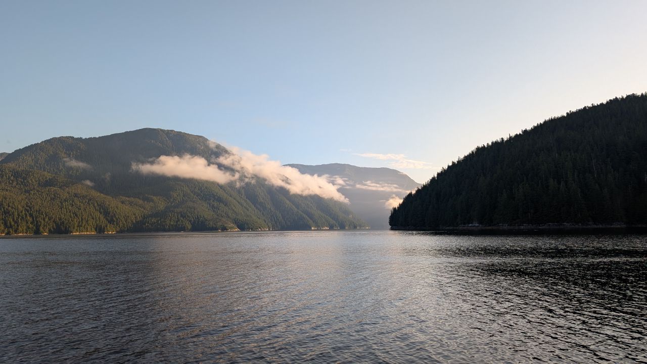 Morning clouds hovering low over forested mountains along the channel to Swanson Bay