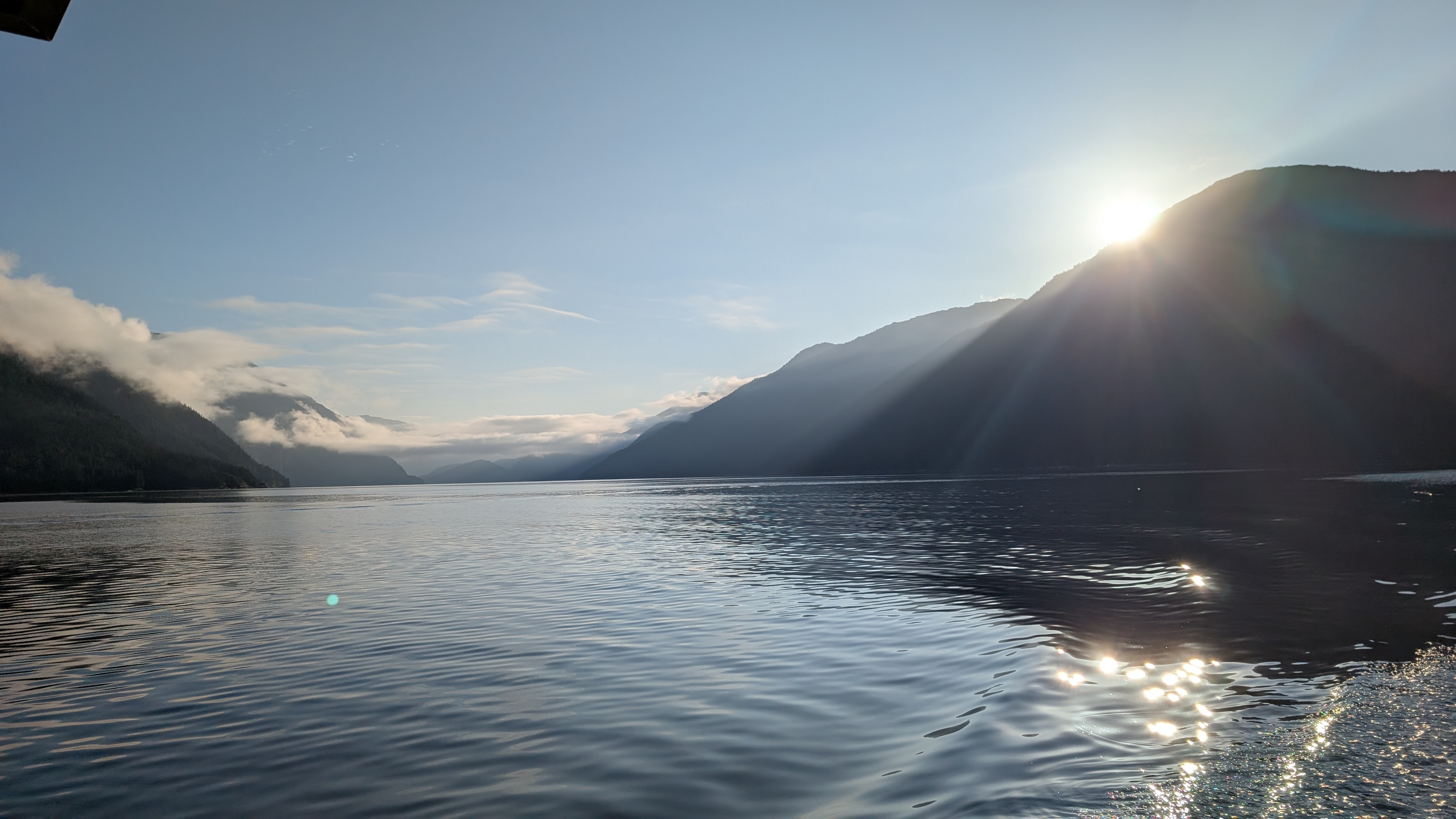 Sun rising over the mountains with light sparkling on the glassy water of the channel