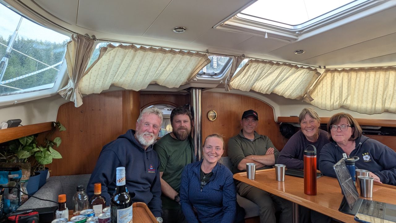Flotilla crew of six gathered around the salon table below deck on SV Yahara at Rescue Bay