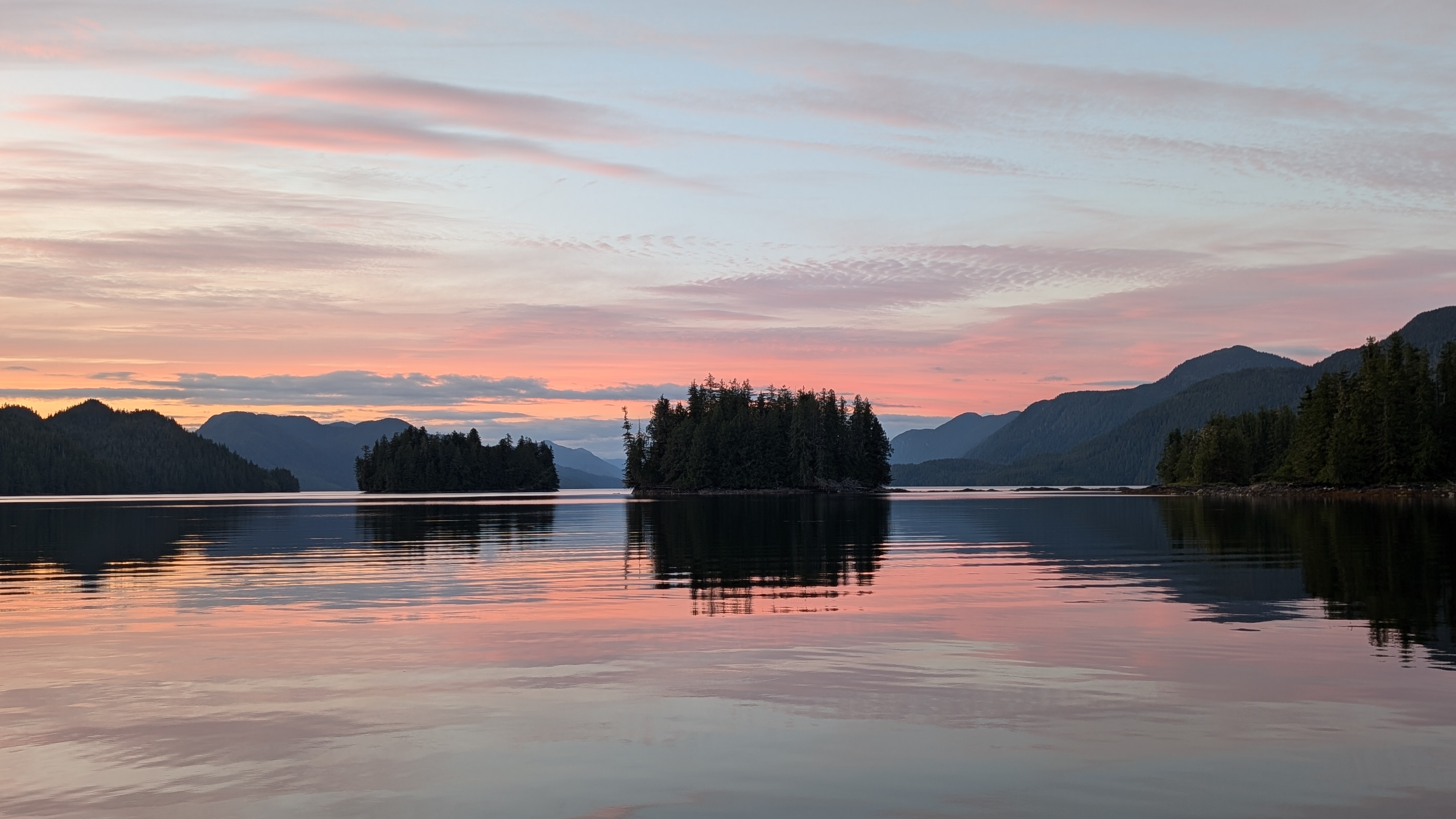 Stunning pink sunset reflecting on glassy water with forested islands at Rescue Bay