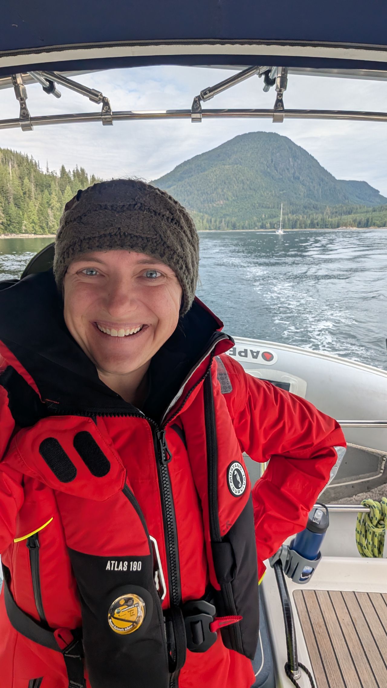 Rachel grinning in her red foul weather gear at the helm after navigating Green Point Rapids solo for the first time