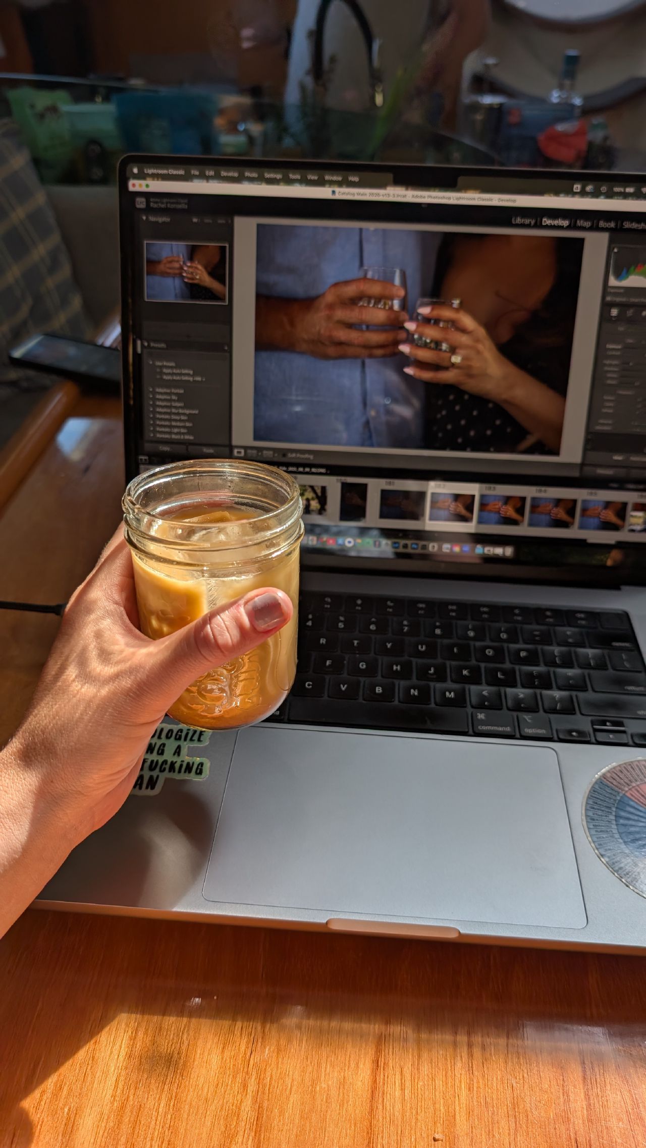 Rachel editing proposal photos in Lightroom with an iced coffee in a mason jar on the boat