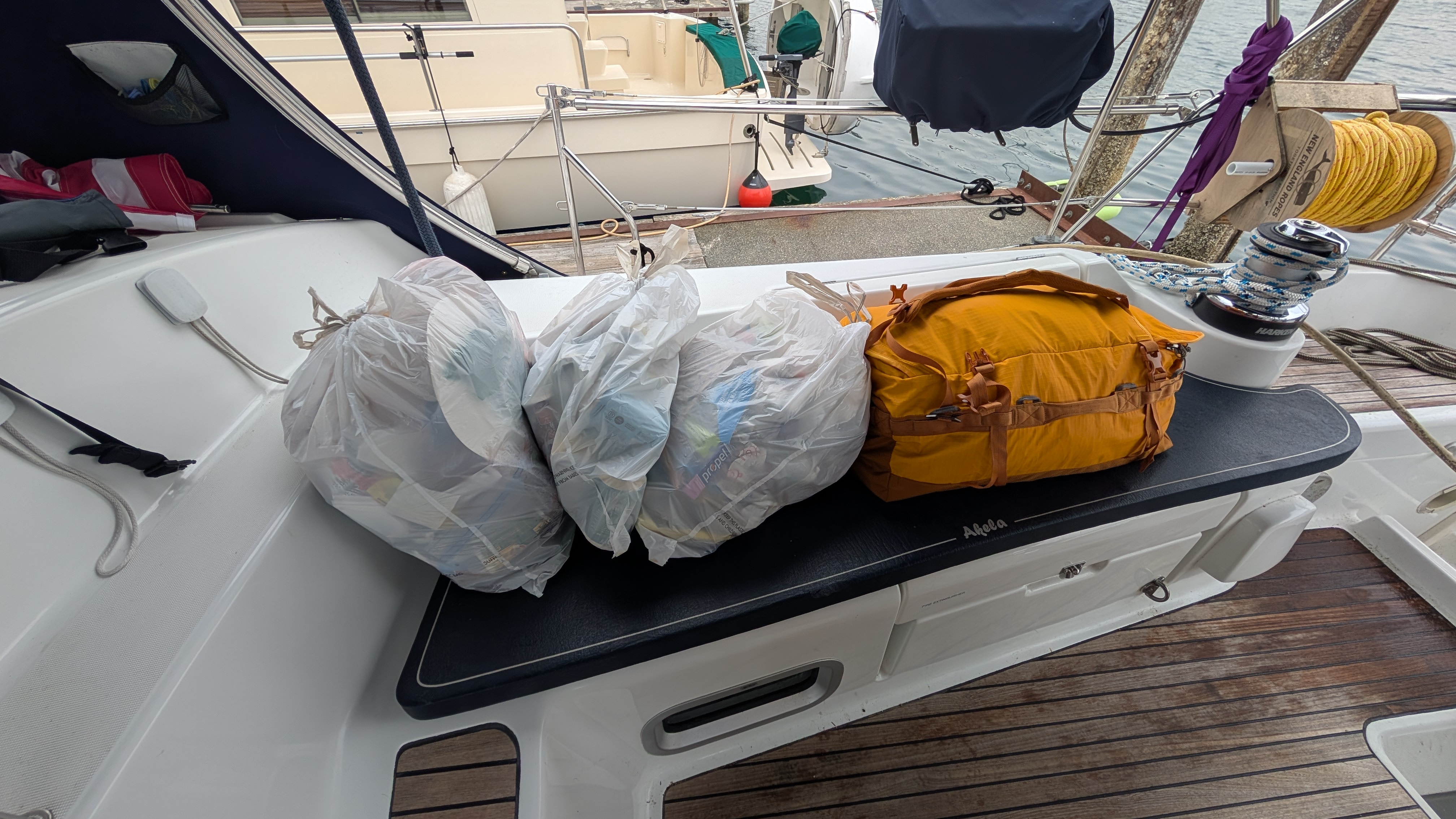 Three bags of garbage and recycling plus a duffel bag lined up on the cockpit seat ready to go ashore