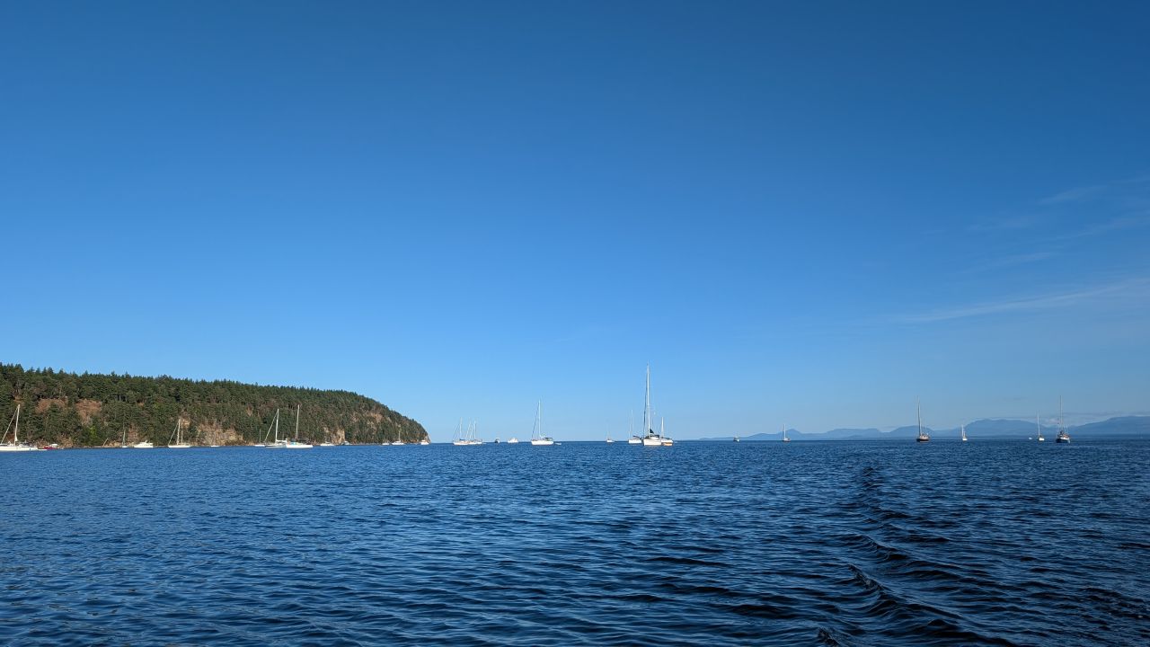 Sailboats anchored in the deep blue waters of Tribune Bay under a clear blue sky on Hornby Island
