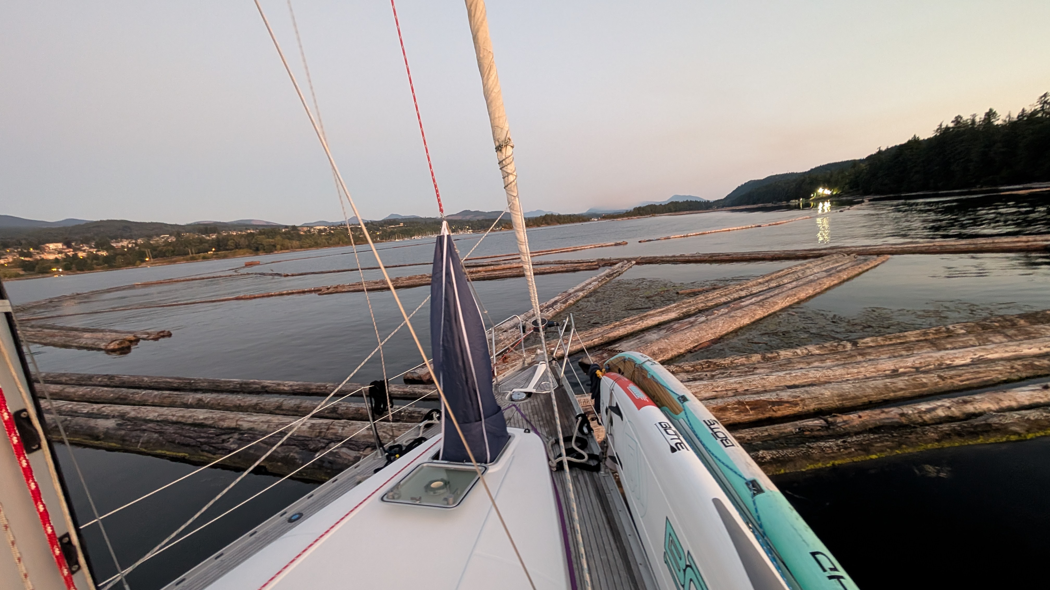 View from the bow of SV Yahara surrounded by logs from a drifting log boom in Ladysmith anchorage at dawn