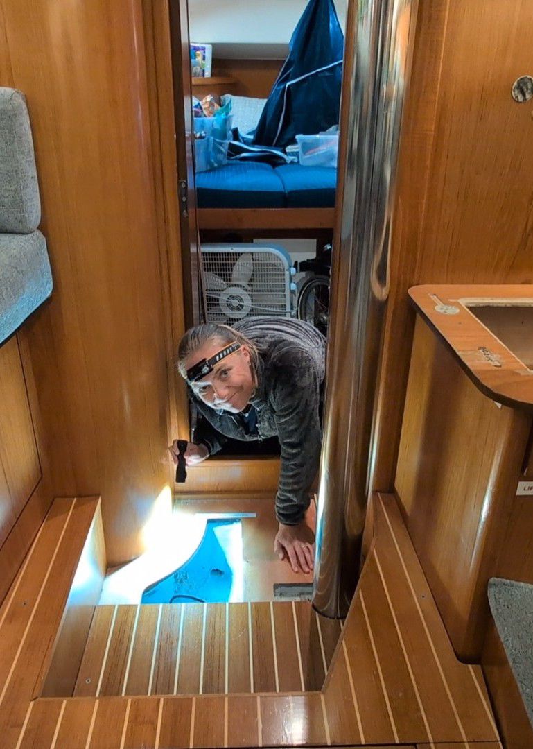 Rachel smiling with a headlamp while emerging from inspecting the bilge for a water leak