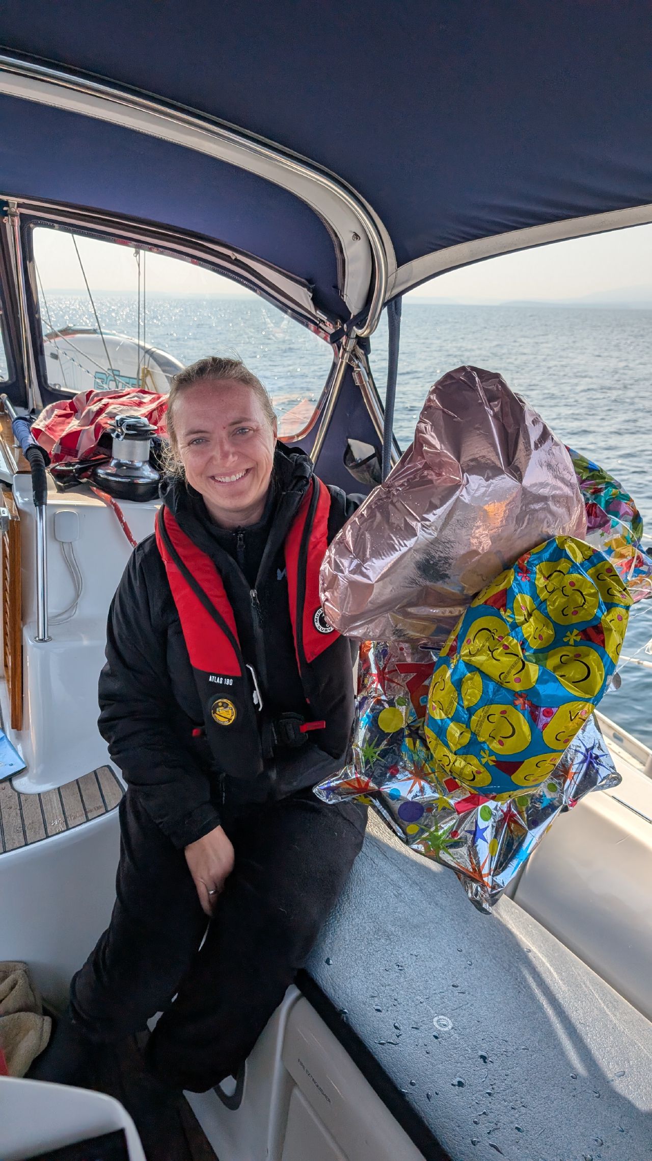 Rachel smiling in the cockpit holding a bunch of mylar balloons rescued from the Strait of Juan de Fuca