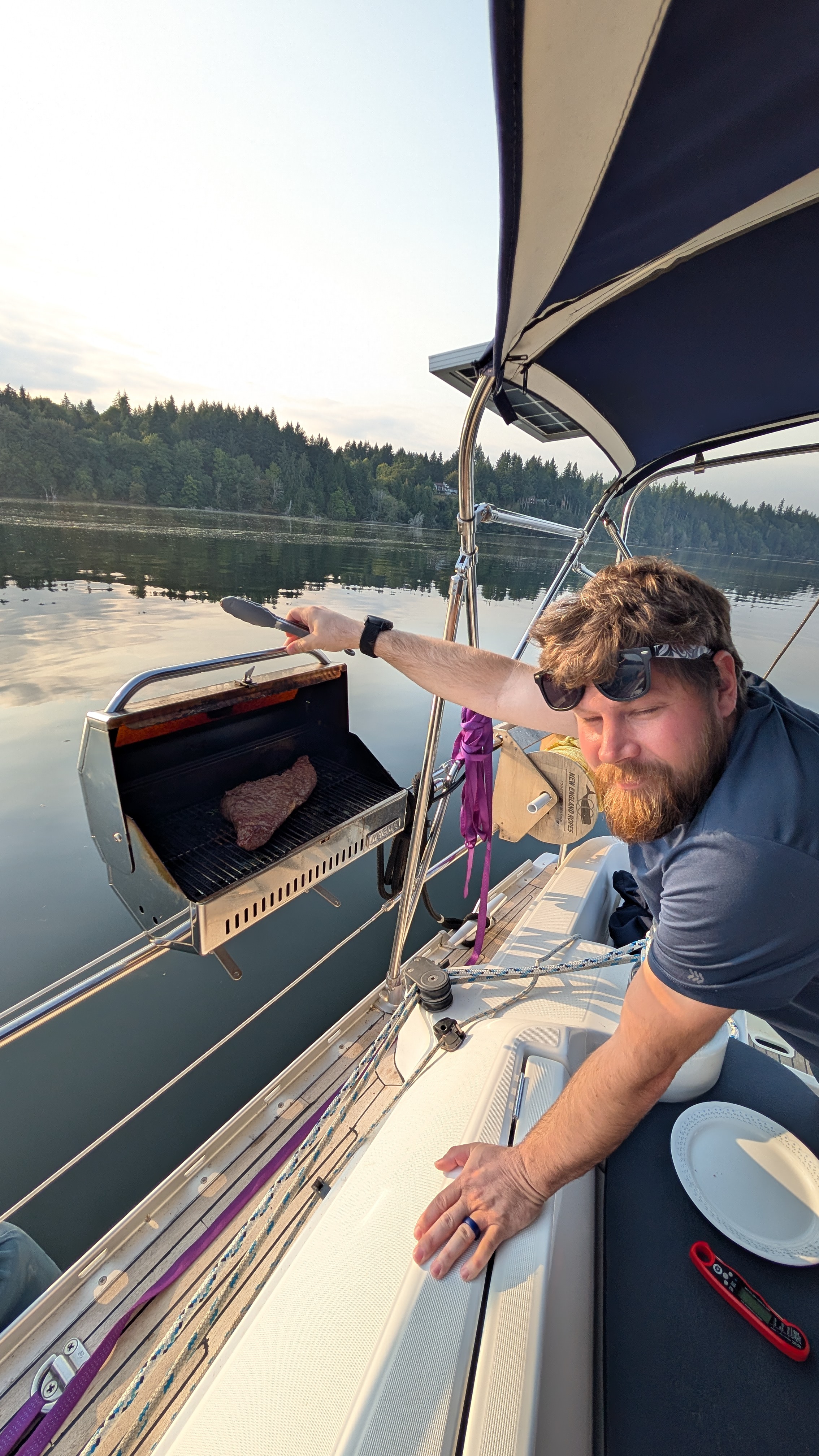 Brian grilling a steak on the rail-mounted BBQ aboard SV Yahara at McMicken Island anchorage