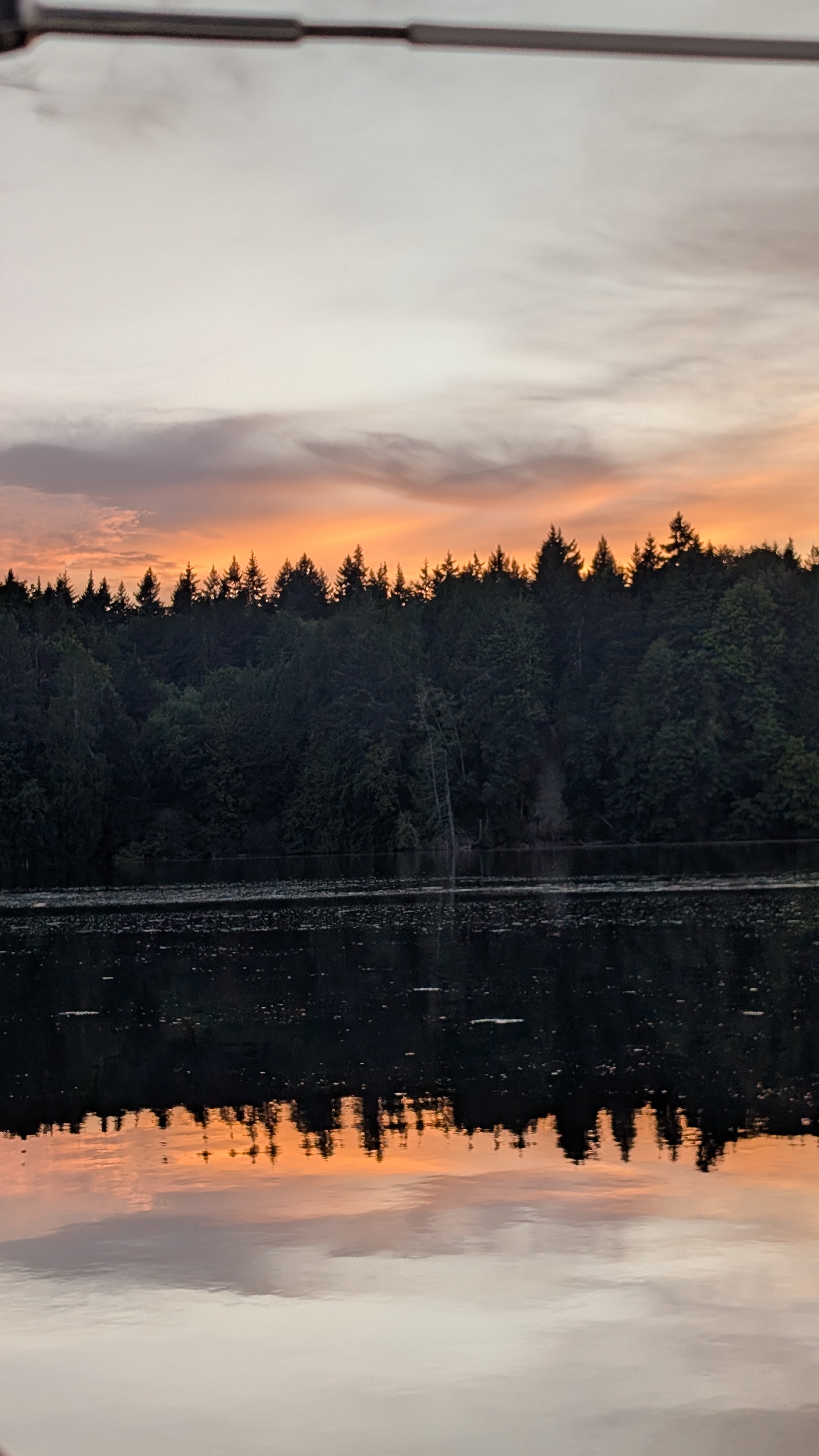 Orange sunset glowing above the treeline and reflecting in the still water at McMicken Island